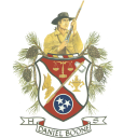 Daniel Boone High School Logo - an image of Daniel Boone wearing a dark hat and wielding a rifle. Below is a crest with scales in the upper fourth, a shoe with wings in the left fourth, a goblet in the right fourth, and a tennessee tri-star logo with white stars in a blue circle and a white outline in the lower fourth. There is a primitive stone axe in the middle of the crest. The crest is surrounded by acorns and branches from a tree with pine needles. Below all of that is a white banner with a red reverse that says "Daniel Boone H S" for Daniel Boone High School.